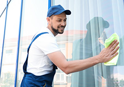 Ein lächelnder Fensterputzer reinigt mit einem Lappen eine Scheibe.